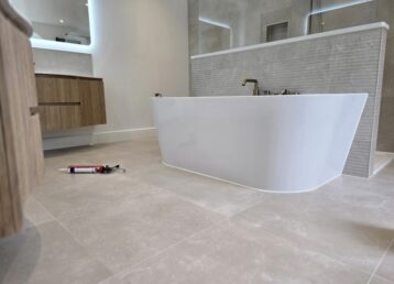 Mastic man applying silicone sealant in a tiled bathroom in Bournemouth